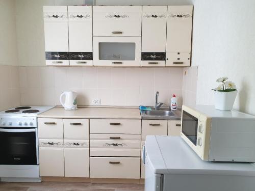 a kitchen with white cabinets and a microwave at Апартаменты Кристалл на Пушкина 12 in Yurga