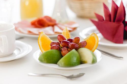 a plate of fruit on a table with a cup of coffee at Hotel Allegro Wien in Vienna