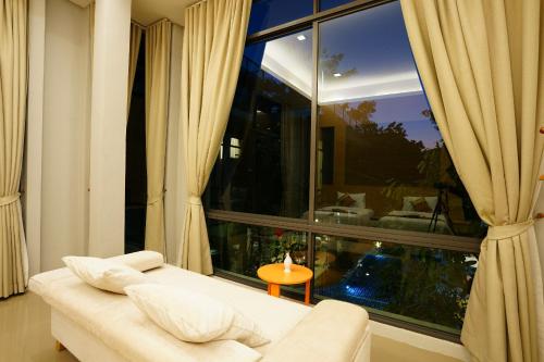 a living room with a white couch and a large window at Treescape Resort Chiangmai in Chiang Mai