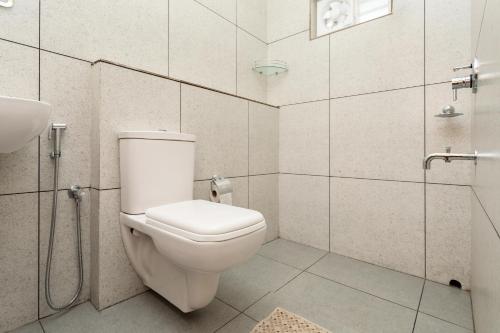 a white bathroom with a toilet and a sink at Poetrie Homestay in Ernakulam