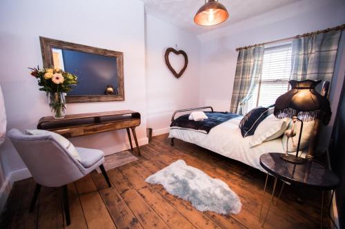 sypialnia z łóżkiem, krzesłem i lustrem w obiekcie 43 BBEscapes w mieście Merthyr Tydfil