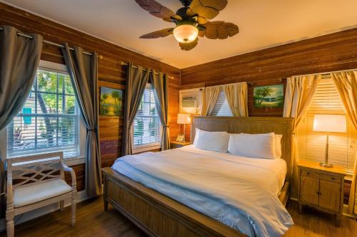 a bedroom with a bed and a ceiling fan and windows at Seascape Tropical Inn in Key West