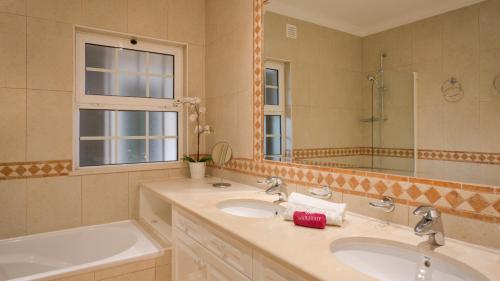 een badkamer met 2 wastafels, een bad en een spiegel bij Joanne in Almancil