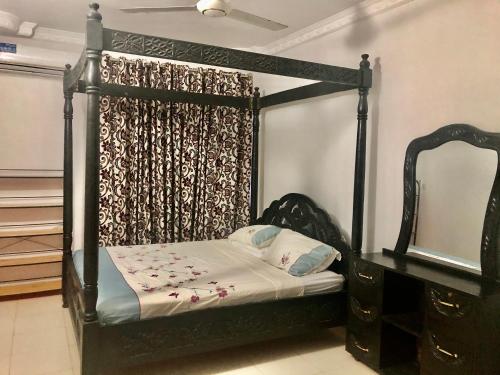 a bedroom with a black canopy bed with a mirror at Michenzani Flat in Zanzibar City