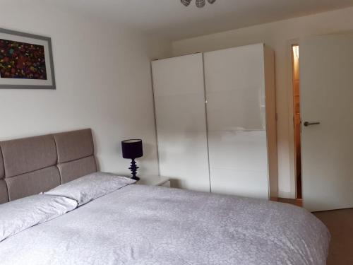 a bedroom with a bed and a large white cabinet at Stylish Wembley Stadium and SSE Arena Apartment, London in London