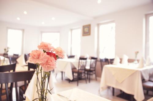 a vase with pink flowers on a table in a restaurant at Hotel Langhans in Abstatt