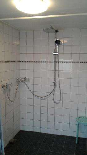 een douche in een wit betegelde badkamer bij 't Hokling in Boazum
