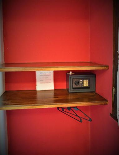 a shelf with a small radio on a red wall at Estancia del Olivo in Chilecito