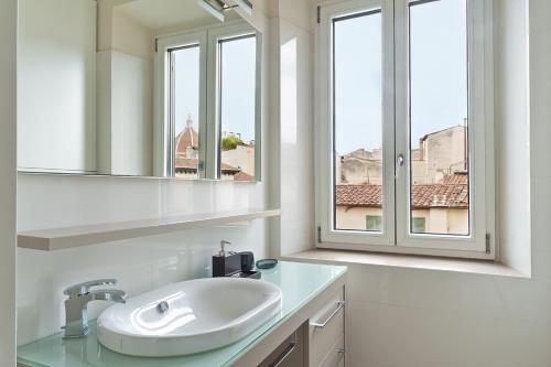ein weißes Badezimmer mit einem Waschbecken und zwei Fenstern in der Unterkunft Anguillara in the Heart of Florence in Florenz