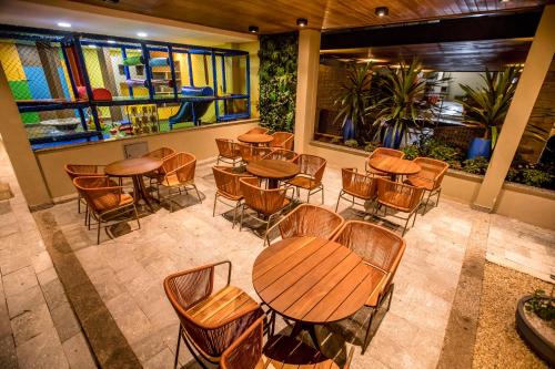an empty restaurant with tables and chairs and windows at Hotel Morada do Sol in Caldas Novas
