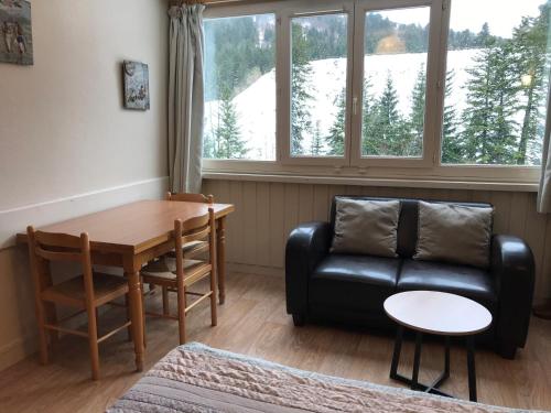 a living room with a black leather couch and a table at RÉSID BEC DE L AIGLE Studio 22 - LE LIORAN in Laveissière