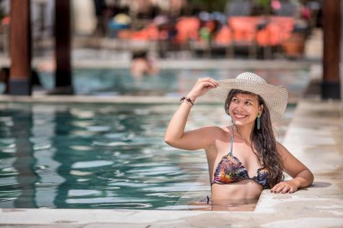 a woman in a bikini and hat in a swimming pool at Hotel Morada do Sol in Caldas Novas