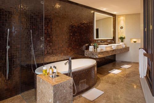 a bathroom with a tub and a shower and a sink at Fairmont Royal Palm Marrakech in Marrakech