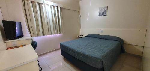 Habitación pequeña con cama y TV. en Villalba Hoteis en Londrina