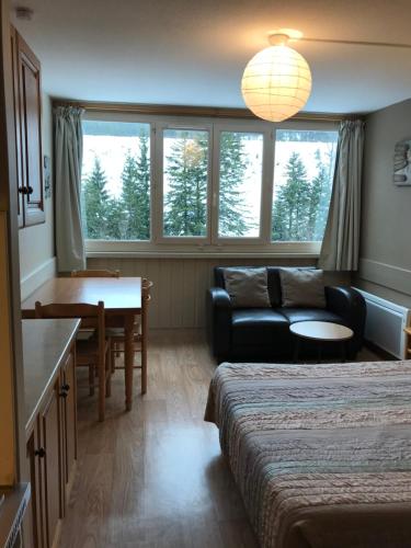 a room with two beds and a couch and a table at RÉSID BEC DE L AIGLE Studio 22 - LE LIORAN in Laveissière