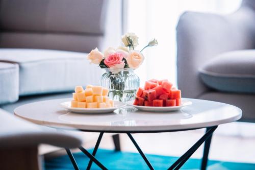 a table with two plates of fruit and a vase of flowers at Holiday Inn Express Ningbo Fenghua by IHG in Ningbo