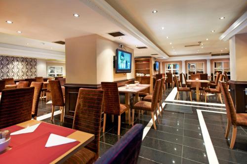 a restaurant with tables and chairs and a television at Royal Eagle Hotel in London