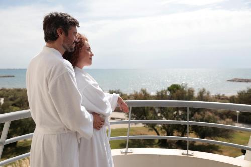a man and woman standing on a balcony overlooking the ocean at Hôtel Les Corallines - Thalasso & Resort in La Grande-Motte