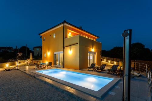 uma piscina em frente a uma casa à noite em House - Villa Skyline em Skrbčići