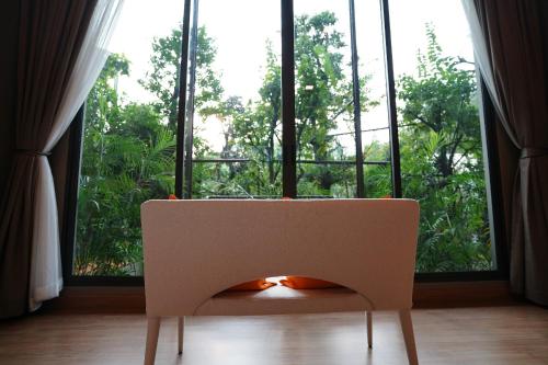 a white chair in front of a large window at Treescape Resort Chiangmai in Chiang Mai