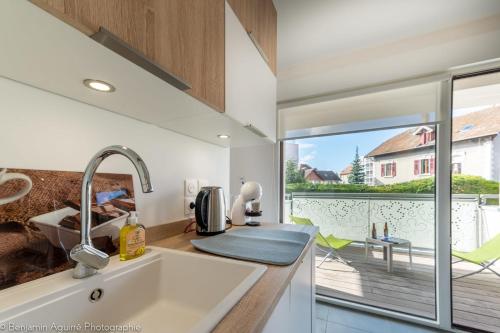 Il comprend une cuisine avec un évier et offre une vue sur une terrasse. dans l'établissement Villa Aniciaca - Recent apartment with private and secure parking, à Annecy