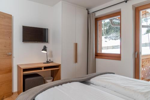 a bedroom with a bed and a desk and a television at Skylodge Alpine Homes in Haus im Ennstal