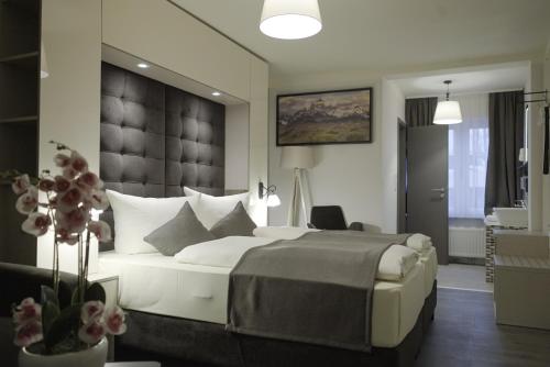 a bedroom with a large white bed with a large headboard at Hotel Bispinger Hof in Bispingen