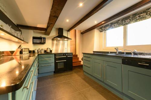 une grande cuisine avec des placards bleus et un évier dans l'établissement Le Moulin de Dingy - House with 6 bedrooms & swimmingpool 20 mn from Annecy, à Dingy-Saint-Clair