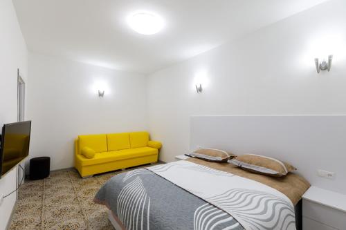 een slaapkamer met een bed en een gele bank bij Уютная одна комнатная квартира на Башлыке in Tasjkent