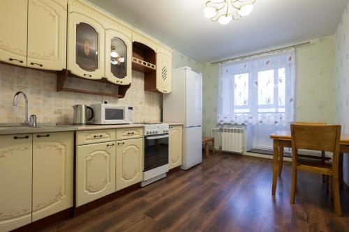 a kitchen with white cabinets and a table and a window at OK! Советская, 69 №1 in Tomsk