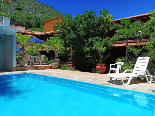 a swimming pool with two chairs and a house at Pousada Porto Praia in Arraial do Cabo