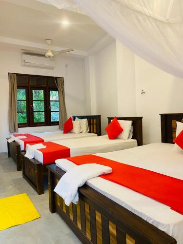a room with four beds with red and white sheets at Villa 45 - Balapitiya in Balapitiya