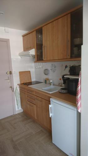 - une cuisine avec des placards en bois et un évier blanc dans l'établissement Beau studio vue Mer Cannes, à Cannes