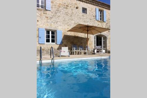 - une piscine avec un parasol en face d'une maison dans l'établissement MAS de la CHICANE, à Blauzac