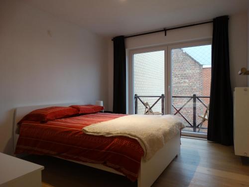 a bedroom with a bed and a large window at Appartement Ter Duinen - Lux Living in De Panne
