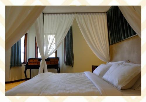 ein Schlafzimmer mit einem weißen Bett mit Vorhängen und einem Klavier in der Unterkunft Mom's Corner in Malang