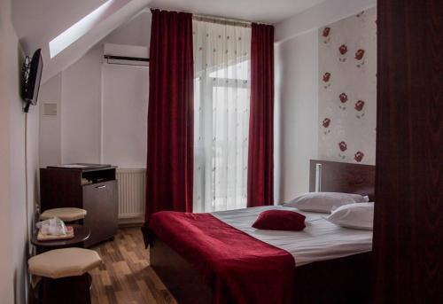 a bedroom with a bed with a red curtain and a window at Pensiunea Octogon in Piatra Neamţ