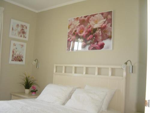 Un dormitorio con una cama blanca con una pintura floral en la pared en Oceanfront Condo with Pool,Breathtaking view, WiFi, en Belnem