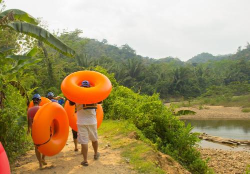 a group of people walking down a dirt road carrying orange tubes at Lamanai Hotel & Marina in Orange Walk
