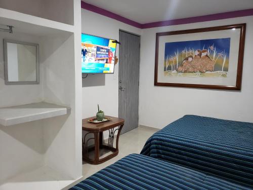 a bedroom with a bed and a table and a picture at Casa Zac Nicte Mx-Estudio SISAL in Cancún