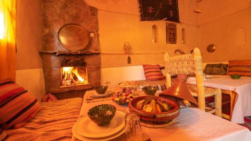 a living room with a table and a fireplace at Dar Essalama Dades in Akhendachou nʼAït Ouffi