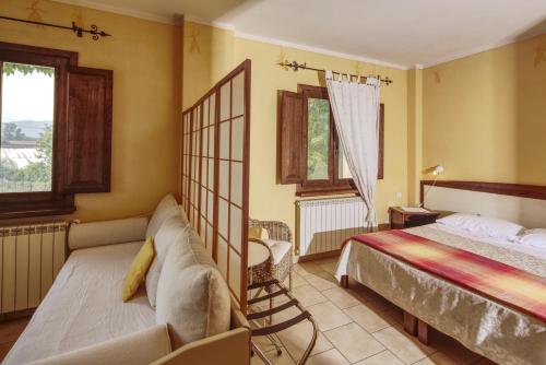 a bedroom with a bed and a couch and windows at Cascina La Commenda in Peveragno
