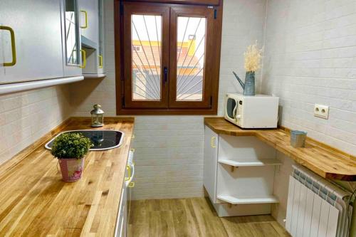 a small kitchen with a sink and a microwave at LaCasitadelaPraderapuntoes in Torremocha de Jarama