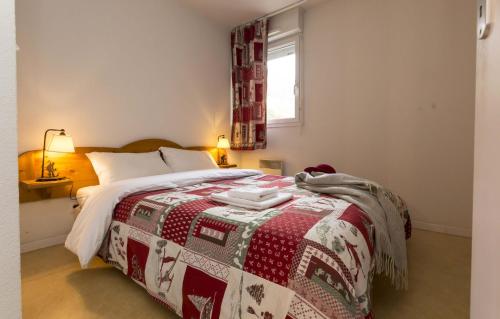 a bedroom with a bed with a red and white blanket at Résidence Odalys Soleil d'Aure in Saint-Lary-Soulan