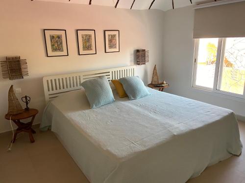 a white bedroom with a large bed with blue pillows at Villa petite cote in Saly Portudal