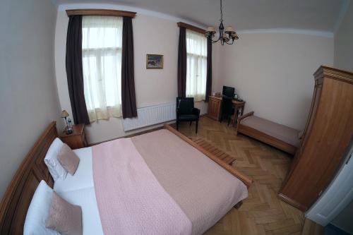 a bedroom with a bed and a desk and two windows at Vila U Varhanáře in Kutná Hora