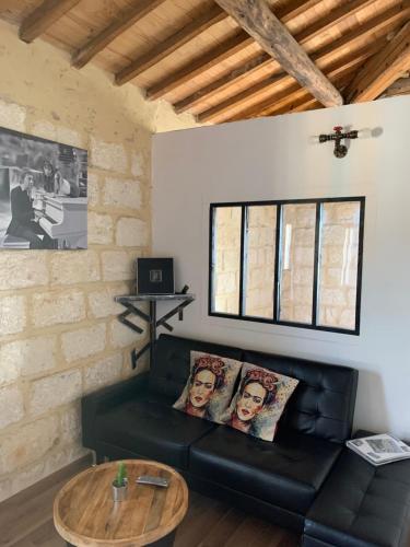sala de estar con sofá negro y mesa de madera en Lou Mirèio, en Aigues-Mortes