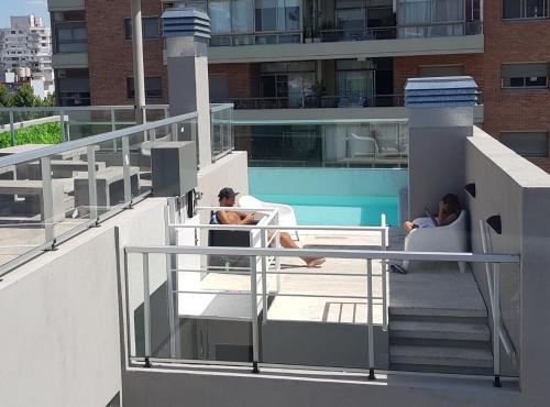 Dos personas sentadas en sillas en el balcón de un edificio en Montañeses 2888 Flat, en Buenos Aires