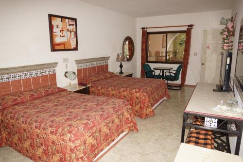 a hotel room with two beds and a table at Hotel Doralba Inn in Mérida