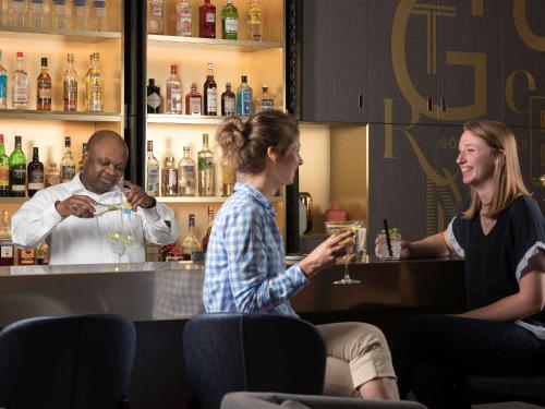 a man and two women sitting at a bar at Novotel Charleroi Centre in Charleroi